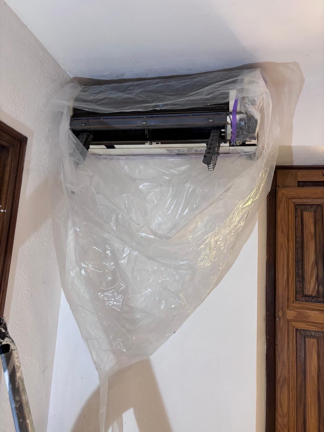 Climatisation ouverte sous une bâche de protection pendant le nettoyage